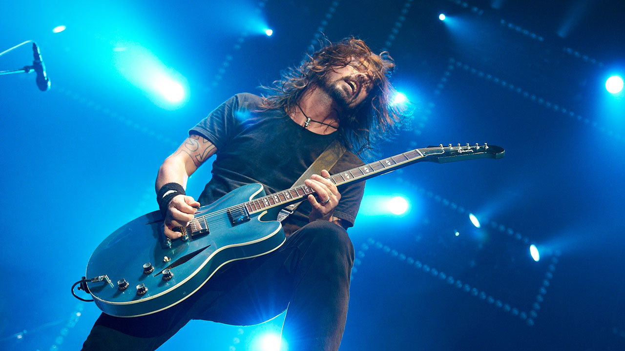 rockstar playing guitar on stage with bright blue lights