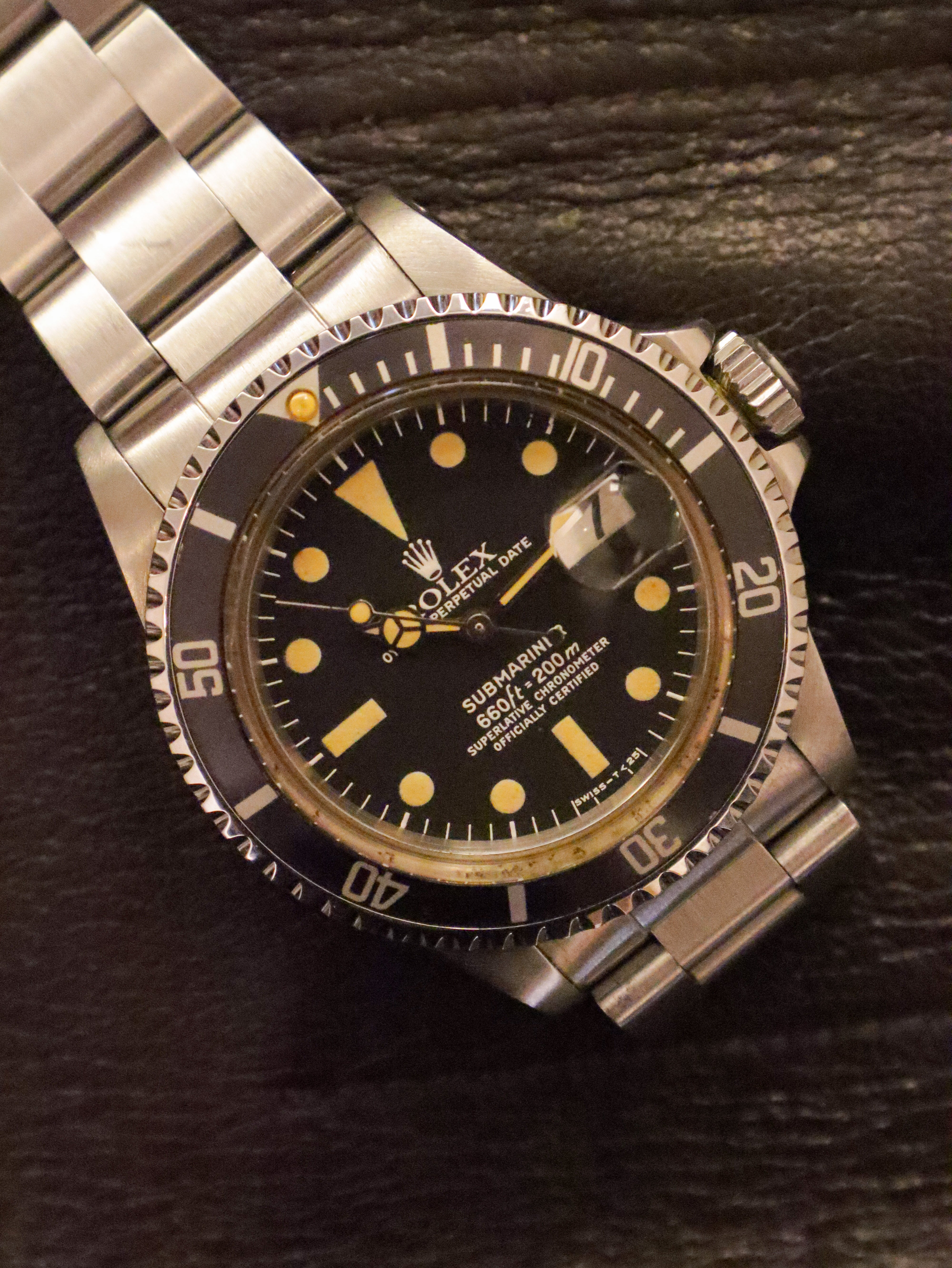 Rolex watch with black dial and silver metal bracelet on a dark background