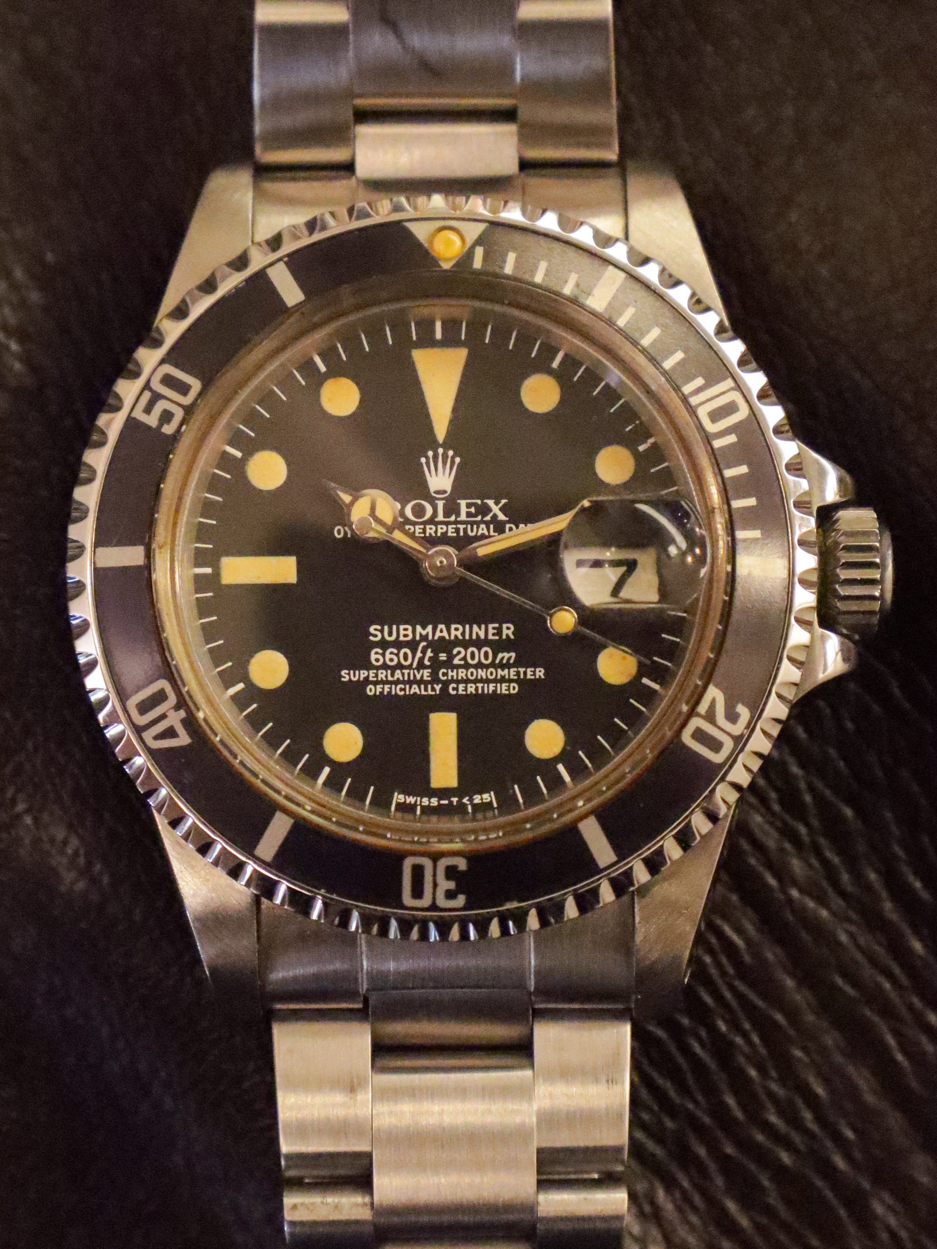 Rolex Submariner watch with black dial and silver metal band on a dark textured background