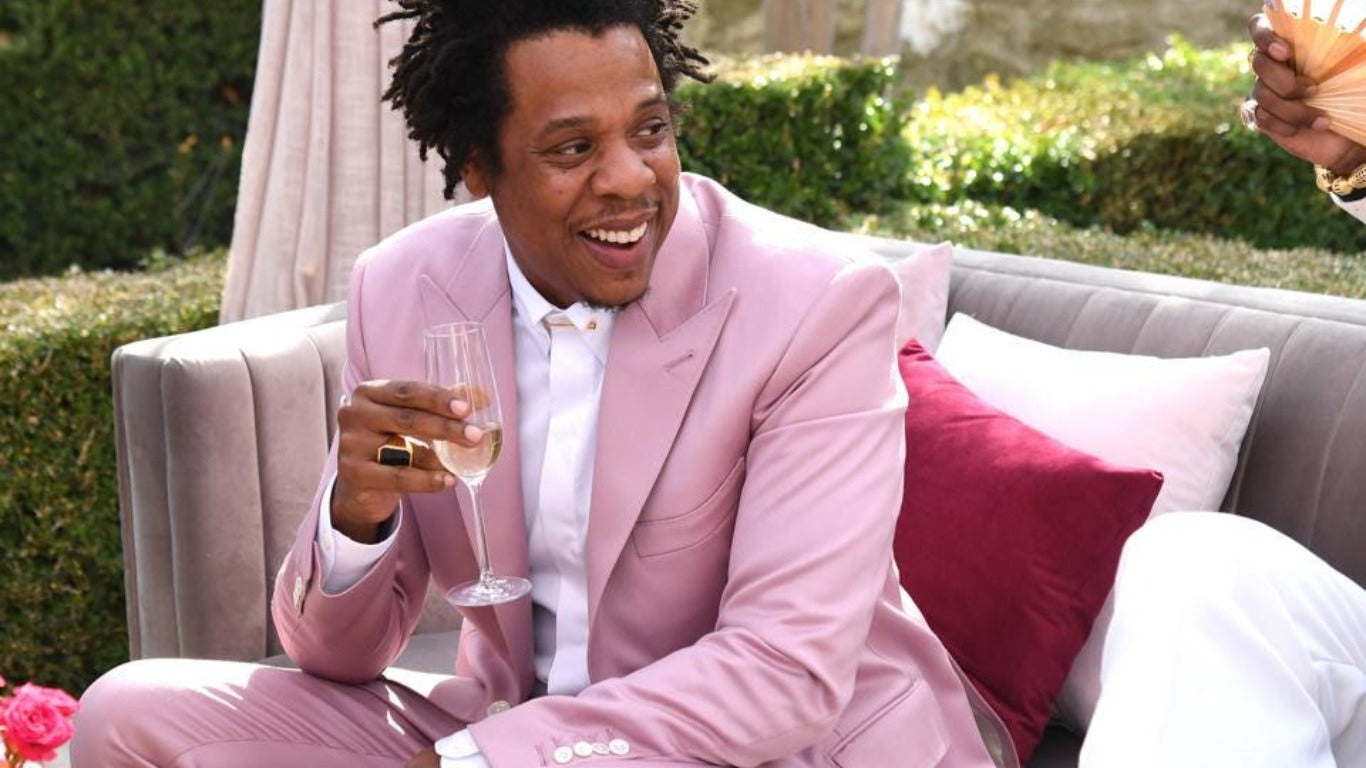Jay Z in a pink suit holding a champagne glass