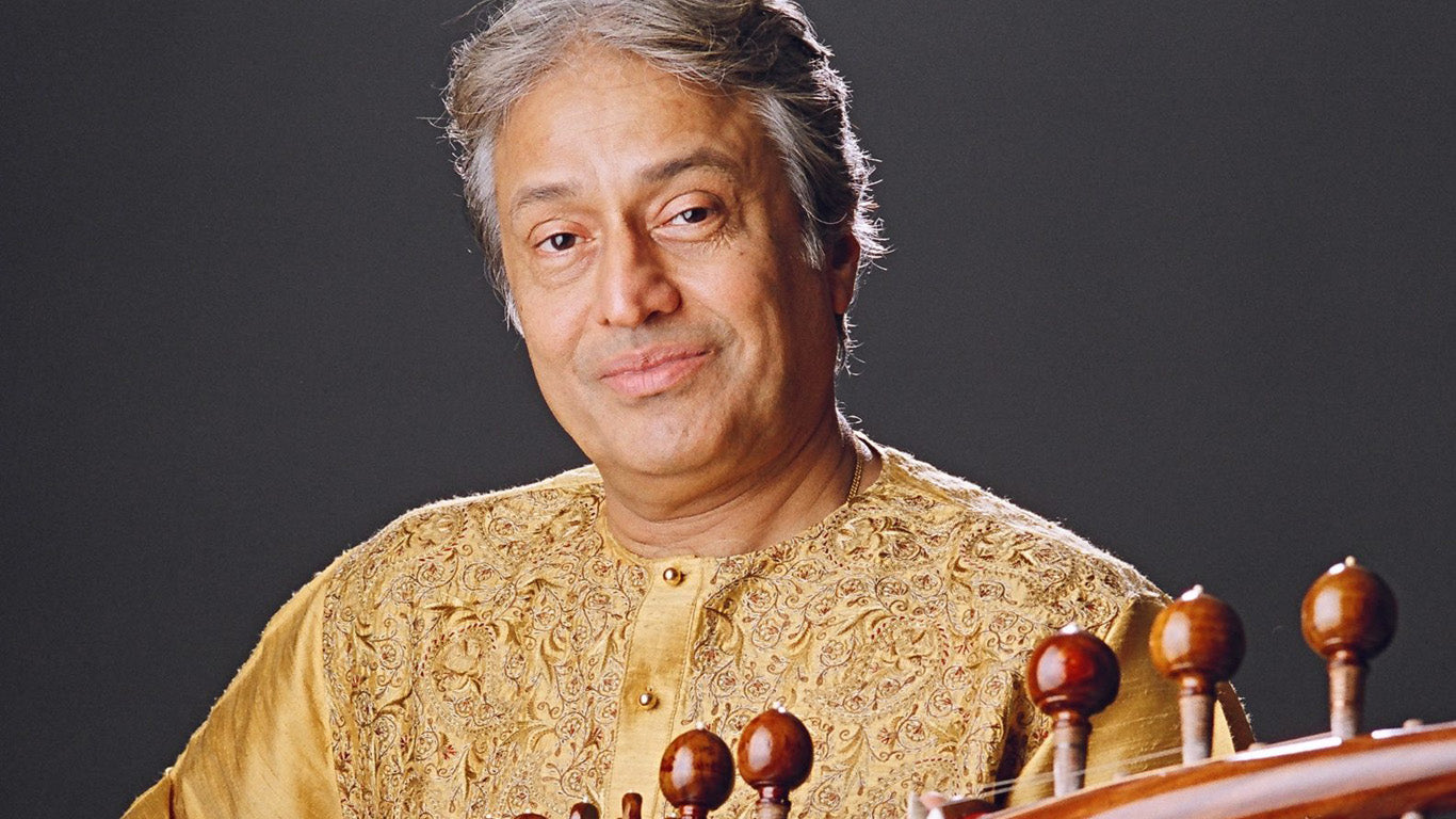 Indian Xlassical Musician Ustad Amjad Ali Khan dressed in a gold kurta holding a rabab instrument