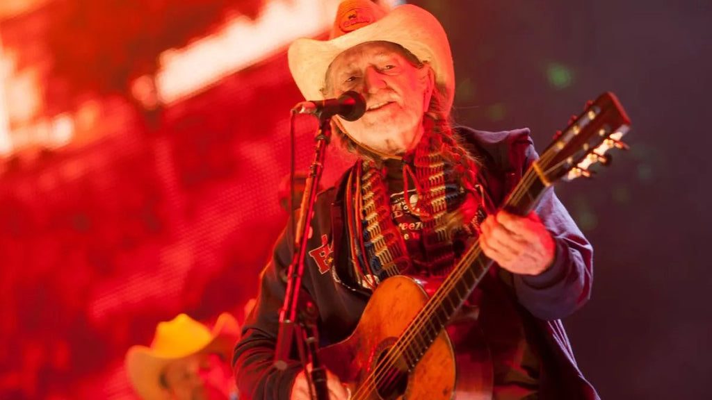 Willie Nelson performing live on stage playing the guitar and singing